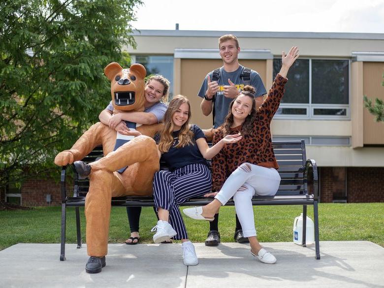 Students sitting on bench next to Lion statue